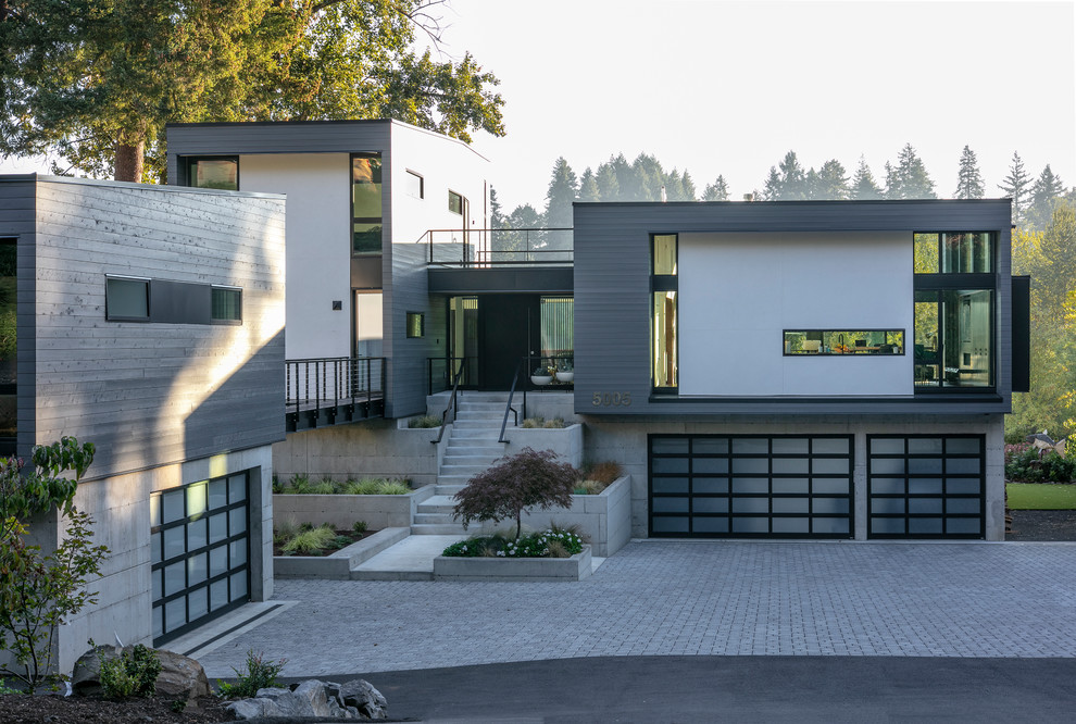 Cette image montre une façade de maison grise design à deux étages et plus avec un revêtement mixte et un toit plat.