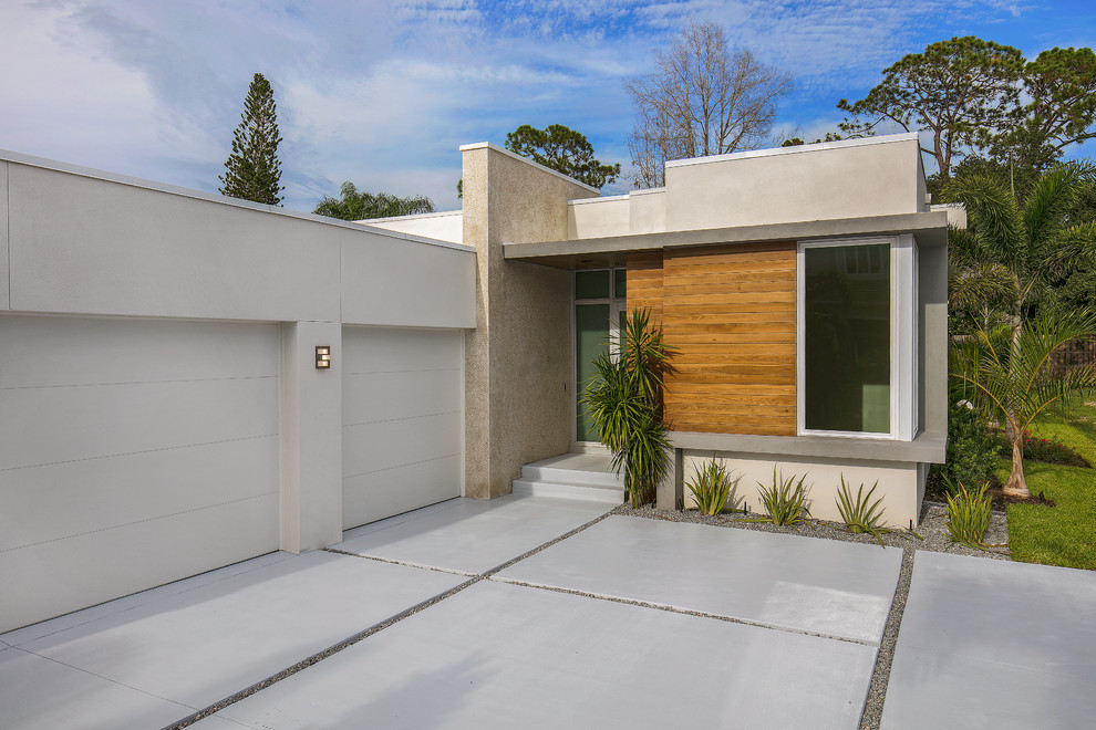 Diseño de fachada de casa blanca actual de tamaño medio de una planta con revestimiento de estuco y tejado plano