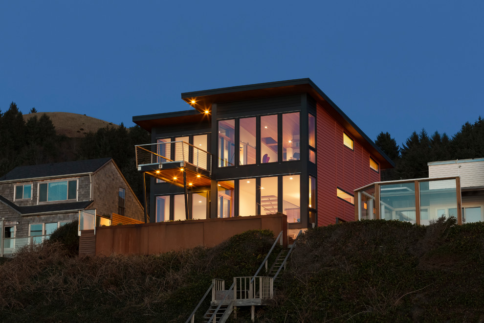 Aménagement d'une façade de maison rouge contemporaine en panneau de béton fibré de taille moyenne et à un étage avec un toit en appentis.