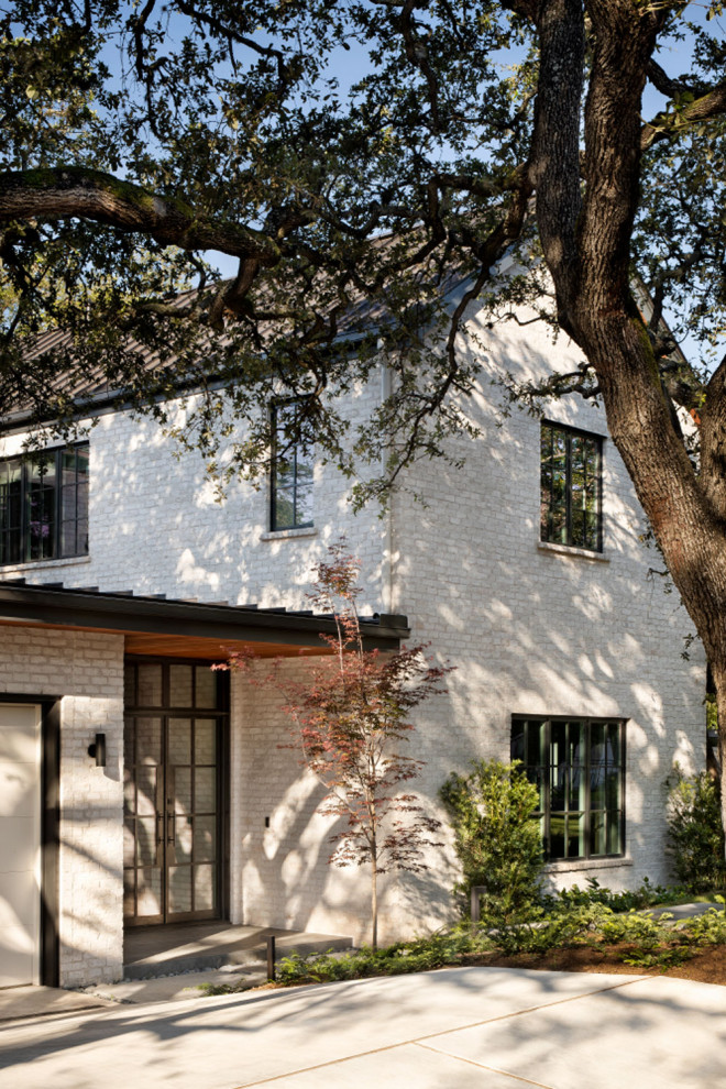Large trendy white two-story brick exterior home photo in Austin with a metal roof