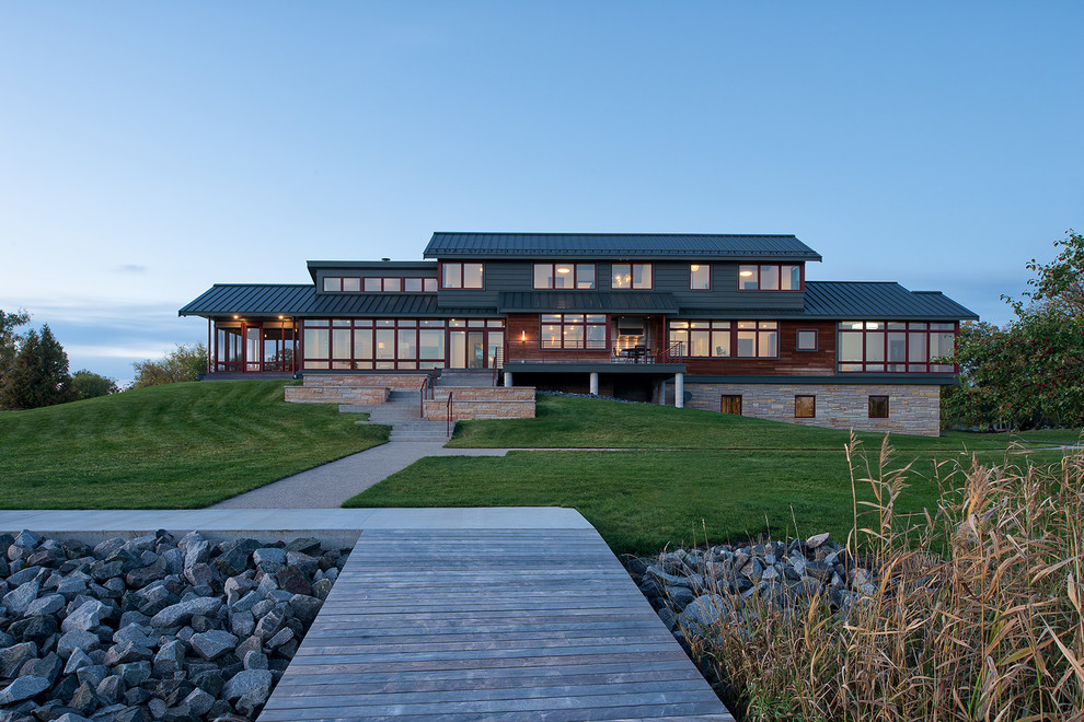 На фото: серый частный загородный дом в стиле неоклассика (современная классика) с разными уровнями, комбинированной облицовкой, двускатной крышей и металлической крышей
