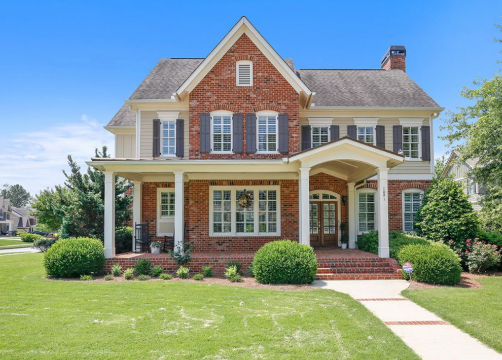 Elegant red two-story brick exterior home photo in Atlanta with a shingle roof