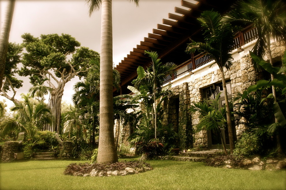 Foto della villa grande beige tropicale a due piani con rivestimento in pietra, tetto piano e copertura in metallo o lamiera