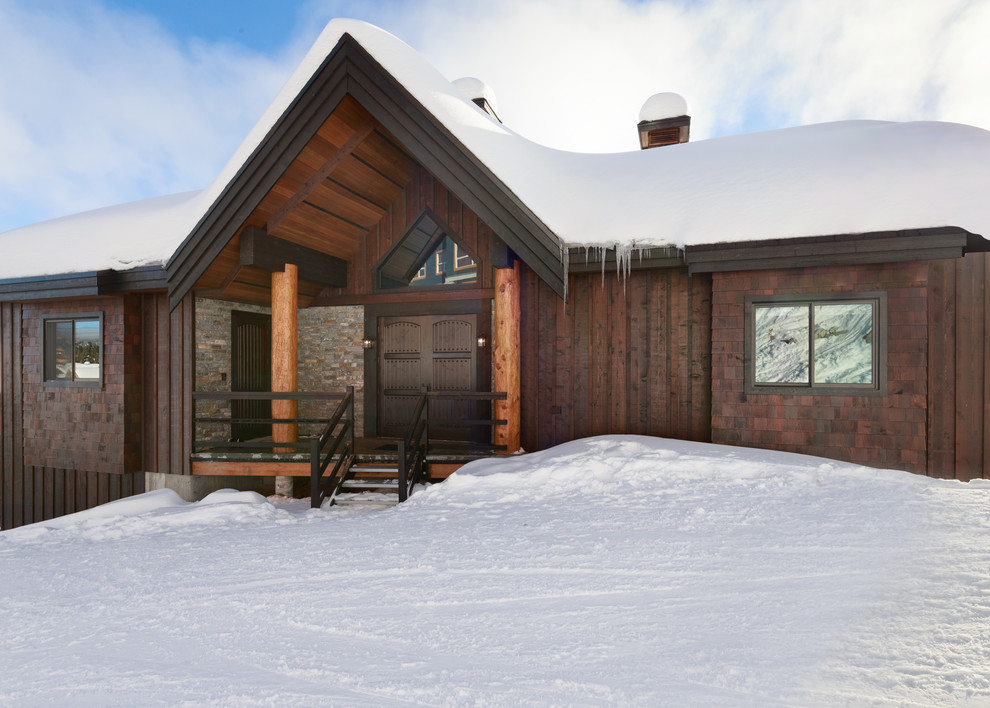 Пример оригинального дизайна: коричневый частный загородный дом в стиле рустика с двускатной крышей и комбинированной облицовкой