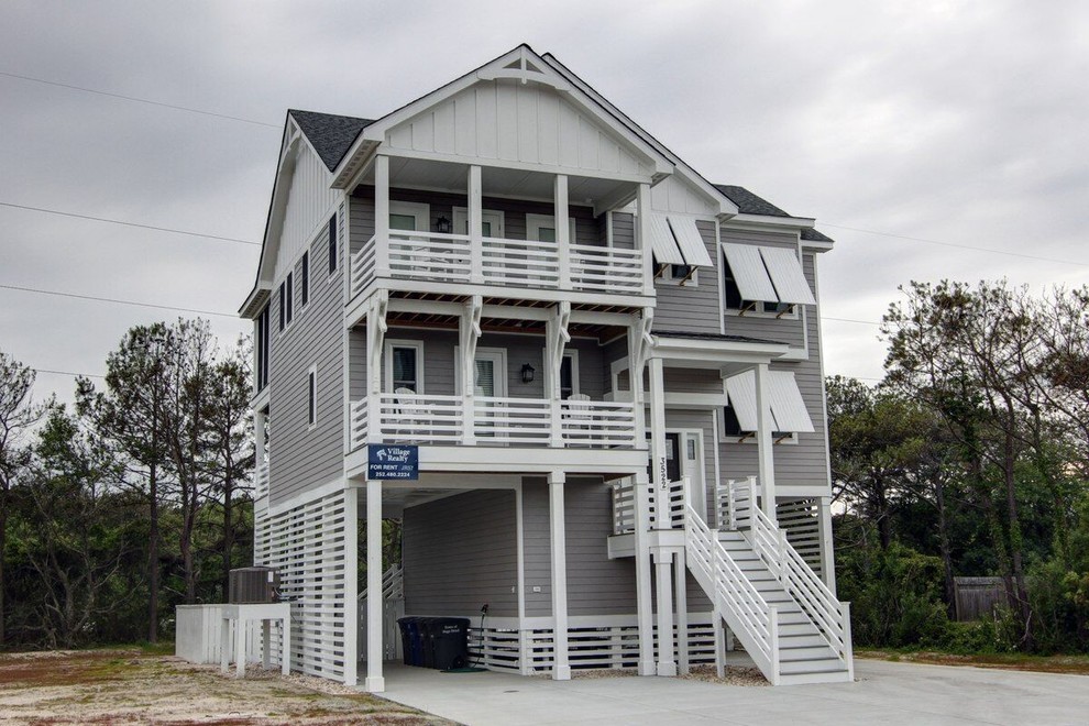 Diseño de fachada gris costera grande de tres plantas con revestimiento de vinilo y tejado a dos aguas