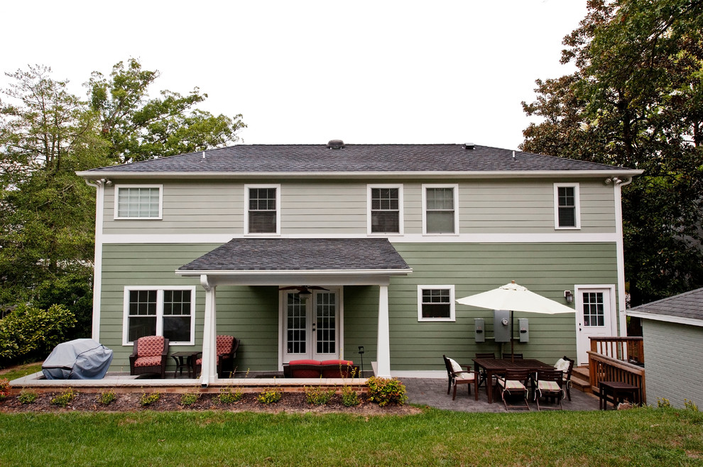 Esempio della villa verde american style a due piani con rivestimento in mattoni, tetto a padiglione e copertura a scandole