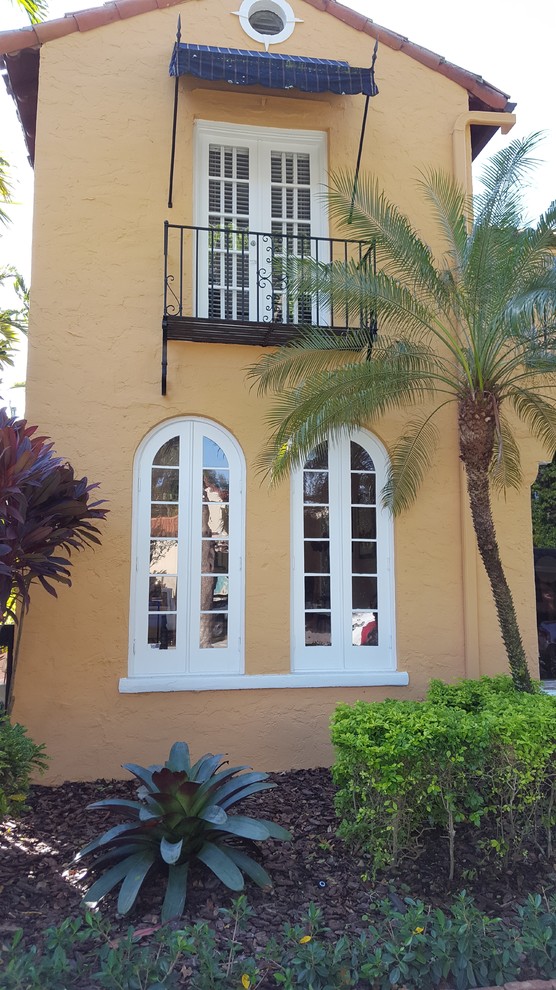 Large traditional yellow two-story stucco gable roof idea in Miami