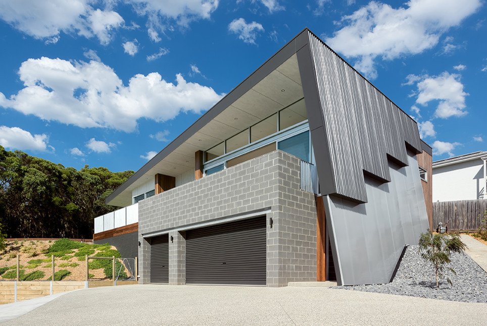 Exemple d'une façade de maison grise tendance en bois de taille moyenne et à un étage avec un toit en appentis et un toit en métal.