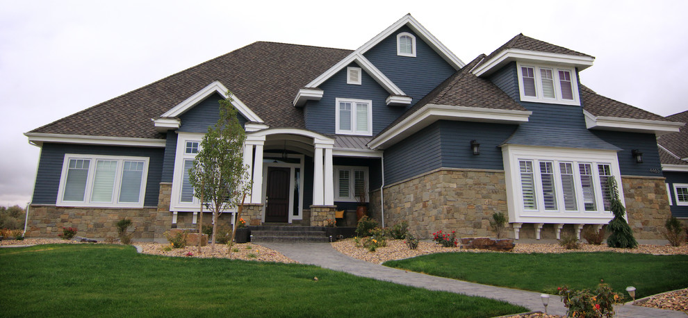 Cette image montre une grande façade de maison bleue chalet à un étage avec un revêtement mixte, un toit à quatre pans et un toit en shingle.