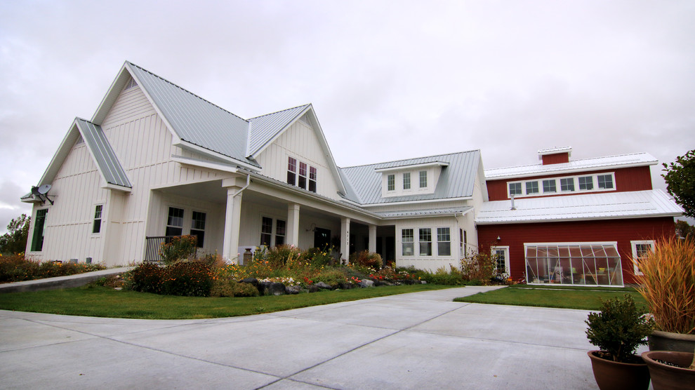 Imagen de fachada de casa blanca rural grande de dos plantas con revestimiento de madera, tejado a dos aguas y tejado de metal