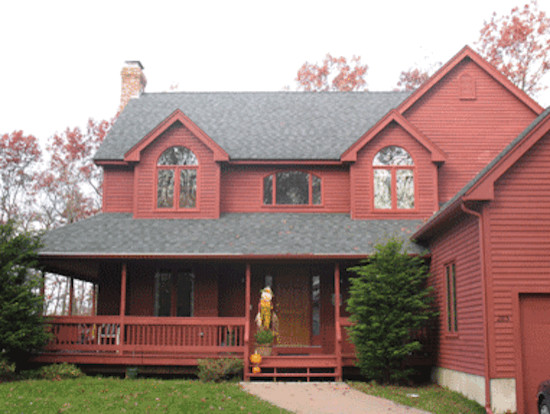 Cette image montre une grande façade de maison rouge en bois à un étage avec un toit à croupette.