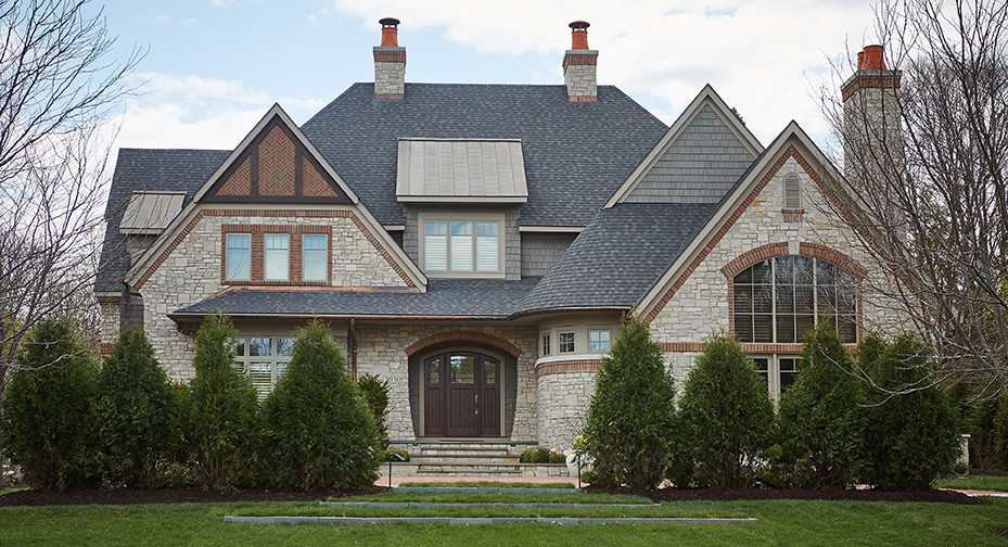Imagen de fachada de casa gris clásica extra grande de tres plantas con tejado de varios materiales, revestimientos combinados y tejado a dos aguas