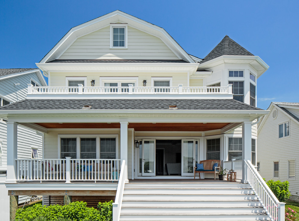 Imagen de fachada de casa beige marinera de dos plantas con tejado a doble faldón y tejado de teja de madera