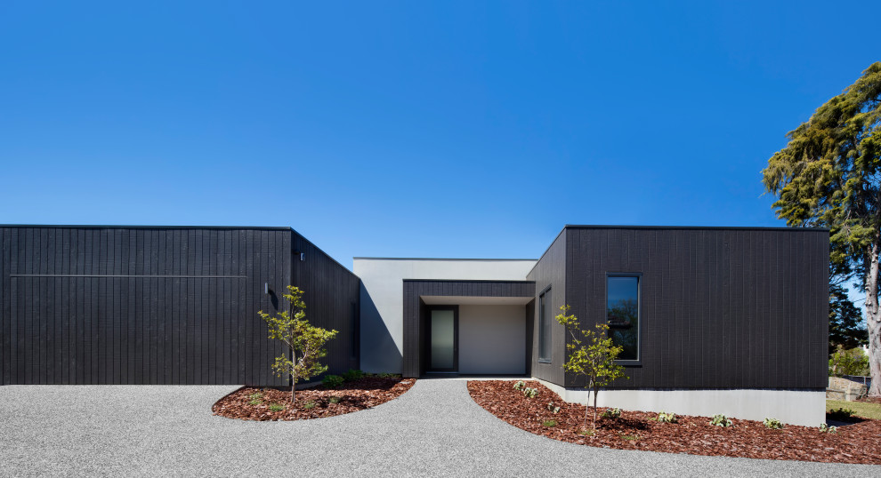 Идея дизайна: одноэтажный, деревянный, черный частный загородный дом среднего размера в стиле модернизм с плоской крышей и металлической крышей