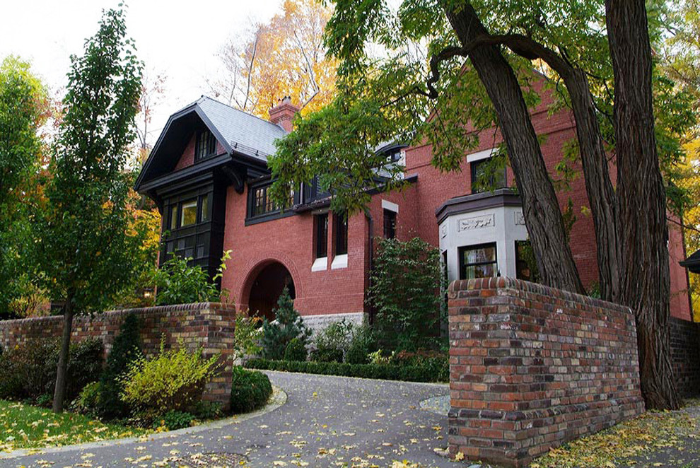 This is an example of a large and red bohemian brick house exterior in Toronto with three floors and a hip roof.