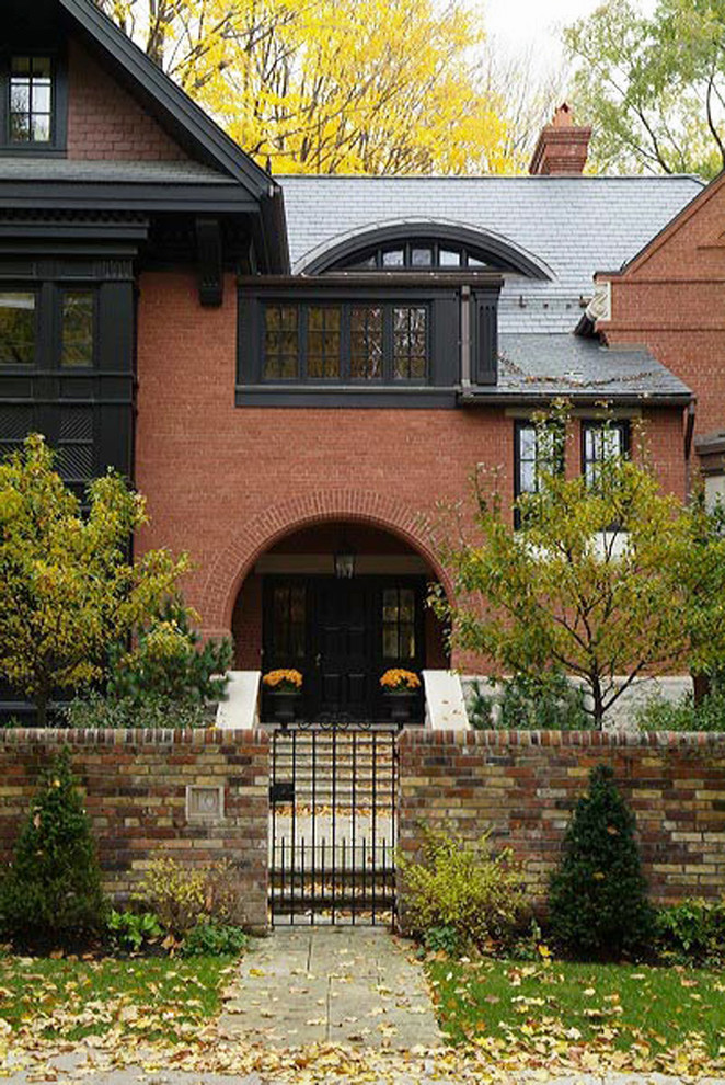 Large and red bohemian brick house exterior in Toronto with three floors and a hip roof.