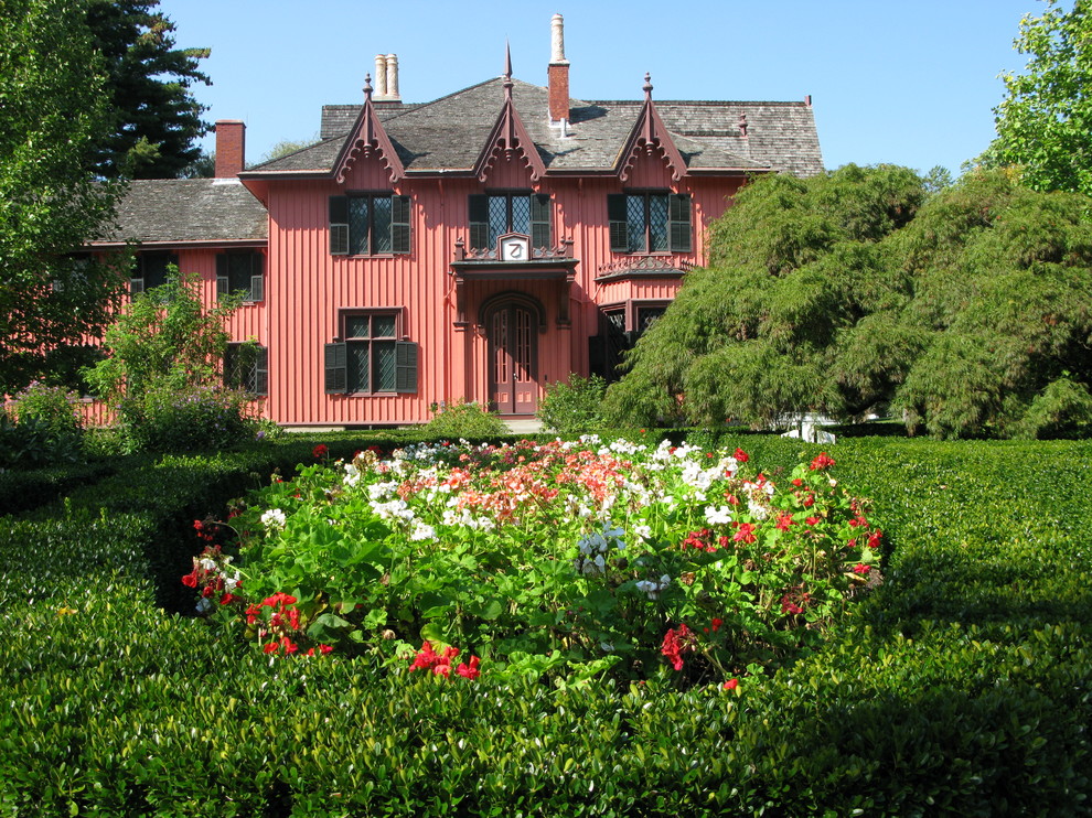 Ejemplo de fachada de casa roja clásica grande de dos plantas con revestimiento de madera y tejado de teja de madera