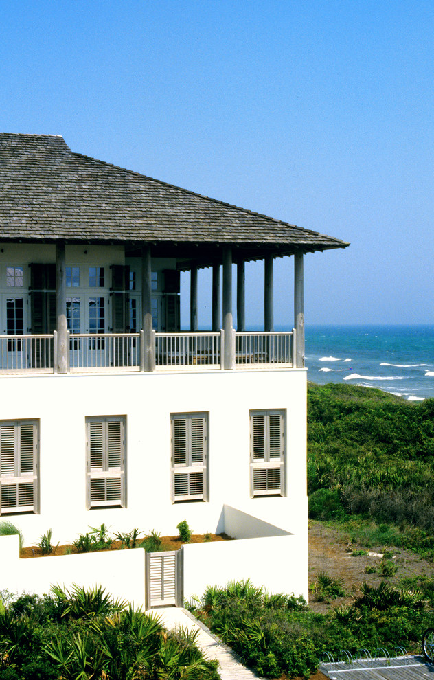 Foto della facciata di una casa grande bianca tropicale a due piani con rivestimento in stucco e tetto a capanna