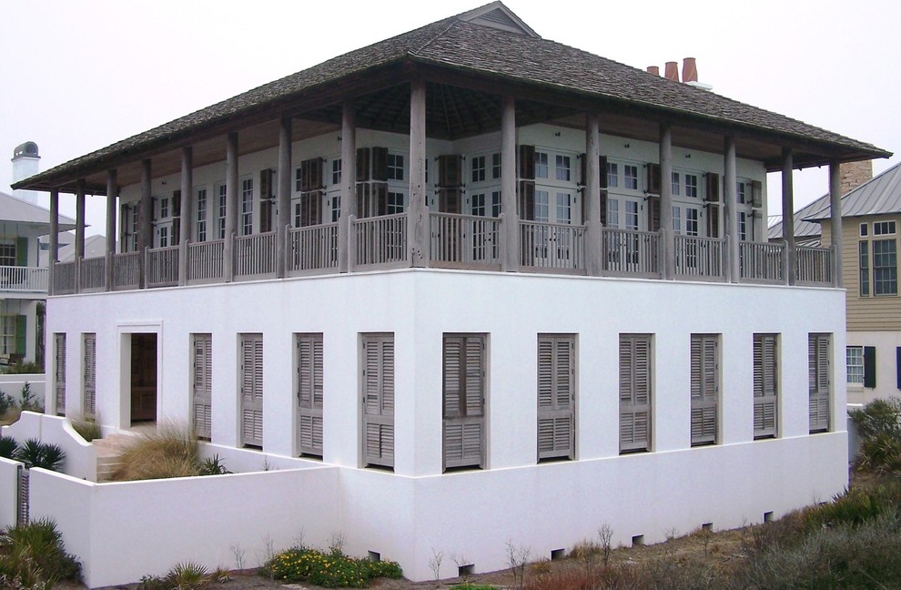Esempio della facciata di una casa grande bianca tropicale a due piani con rivestimento in stucco e tetto a capanna