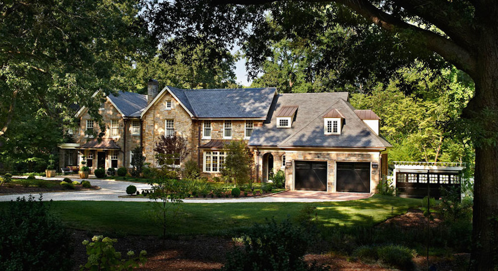 Aménagement d'une façade de maison beige classique en pierre de taille moyenne et à un étage avec un toit à croupette et un toit mixte.