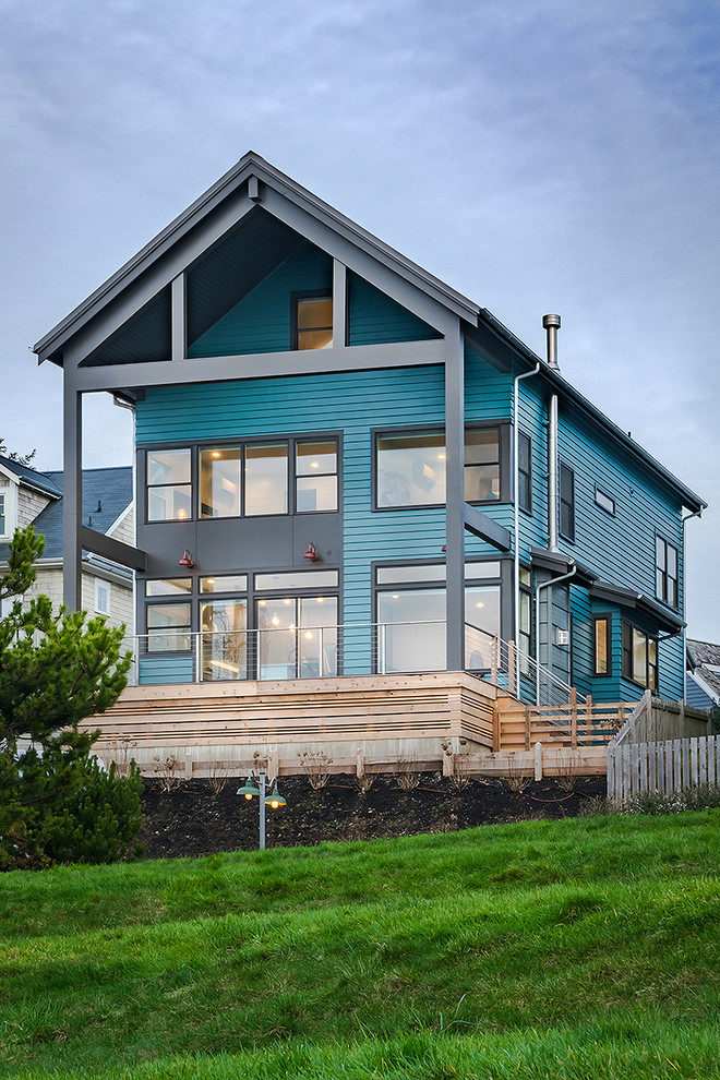 This is an example of a medium sized and blue beach style detached house in Seattle with three floors, concrete fibreboard cladding and a pitched roof.