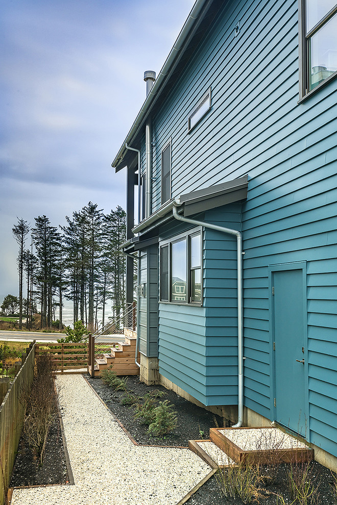 Modelo de fachada de casa azul costera de tamaño medio de tres plantas con revestimiento de aglomerado de cemento, tejado a dos aguas y tejado de metal