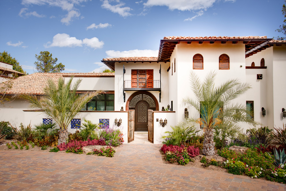 Пример оригинального дизайна: огромный, белый дом в средиземноморском стиле с разными уровнями, облицовкой из цементной штукатурки и вальмовой крышей