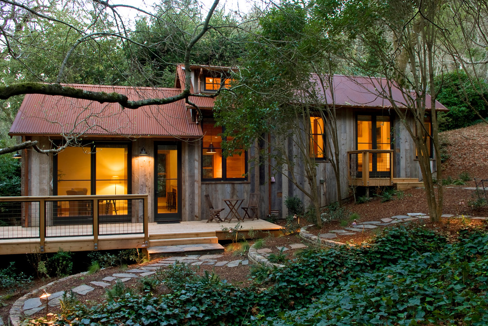 Réalisation d'une petite façade de maison verte chalet en bois de plain-pied avec un toit à deux pans et un toit en métal.