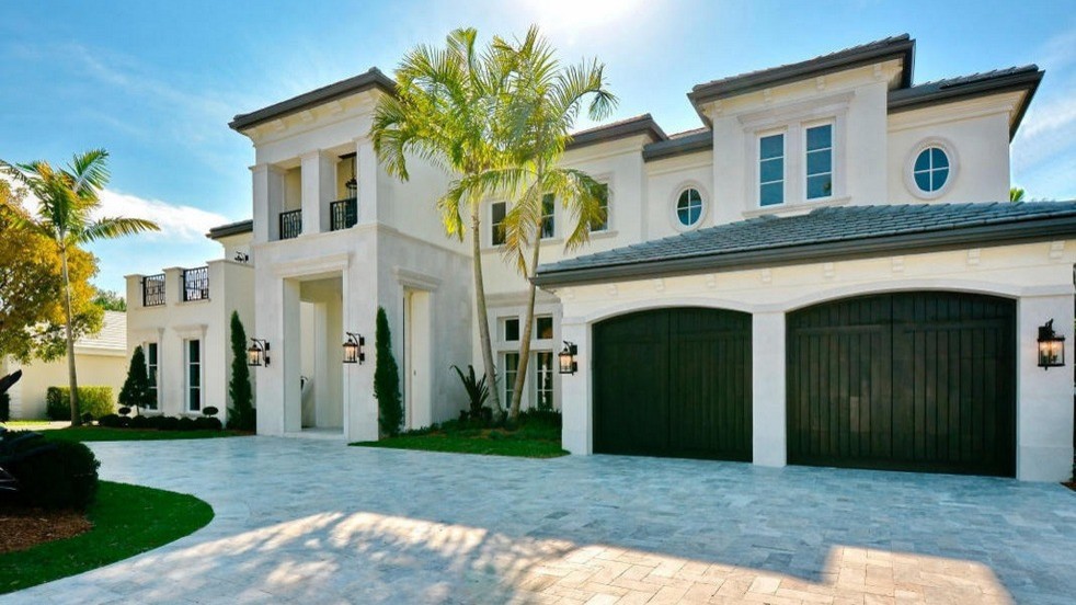 This is an example of a beige mediterranean two floor house exterior in Miami with stone cladding.