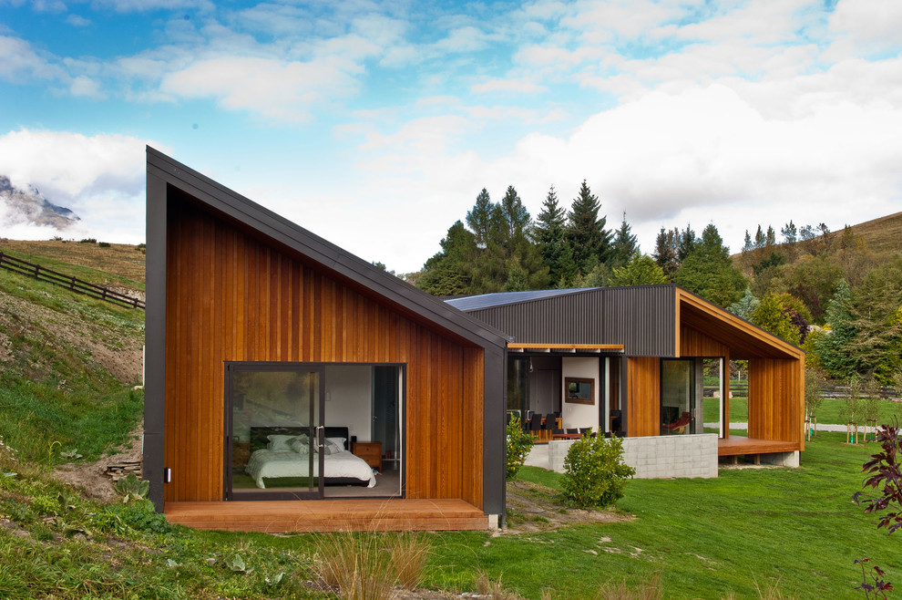 This is an example of a contemporary bungalow house exterior in Dunedin with wood cladding and a lean-to roof.