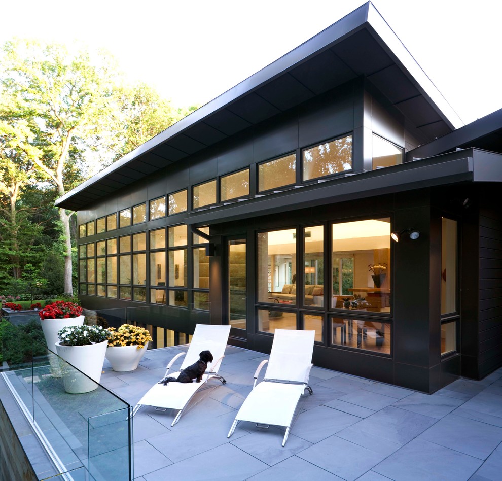 Idée de décoration pour une façade de maison noire design à un étage avec un toit en appentis.