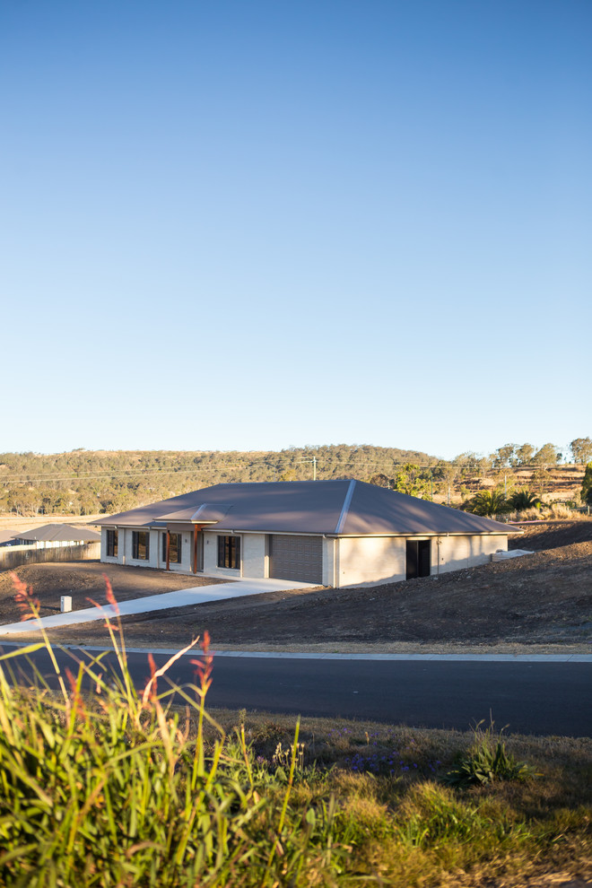 Cette image montre une grande façade de maison marron minimaliste en brique de plain-pied avec un toit en métal.