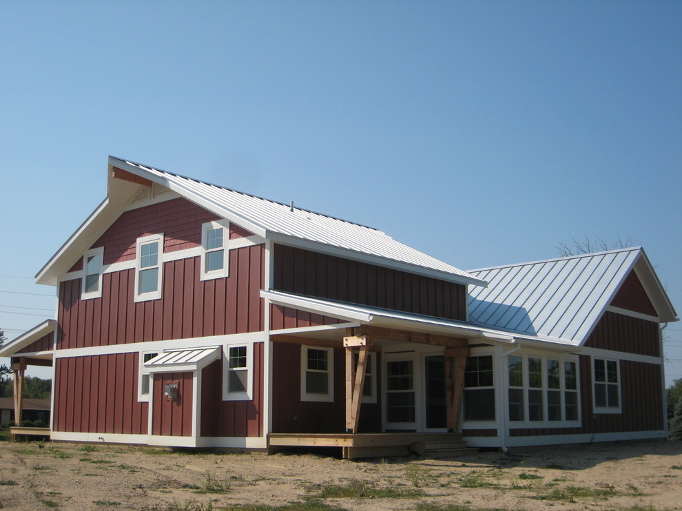 Foto della facciata di una casa piccola rossa country a due piani con rivestimento con lastre in cemento