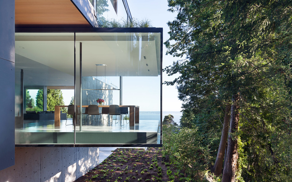 Ispirazione per la facciata di una casa moderna a tre piani con rivestimento in vetro e tetto piano