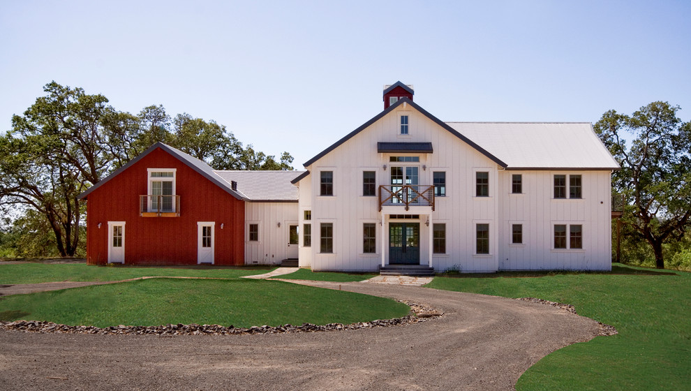Imagen de fachada blanca campestre de tamaño medio de dos plantas con revestimiento de madera y tejado a doble faldón