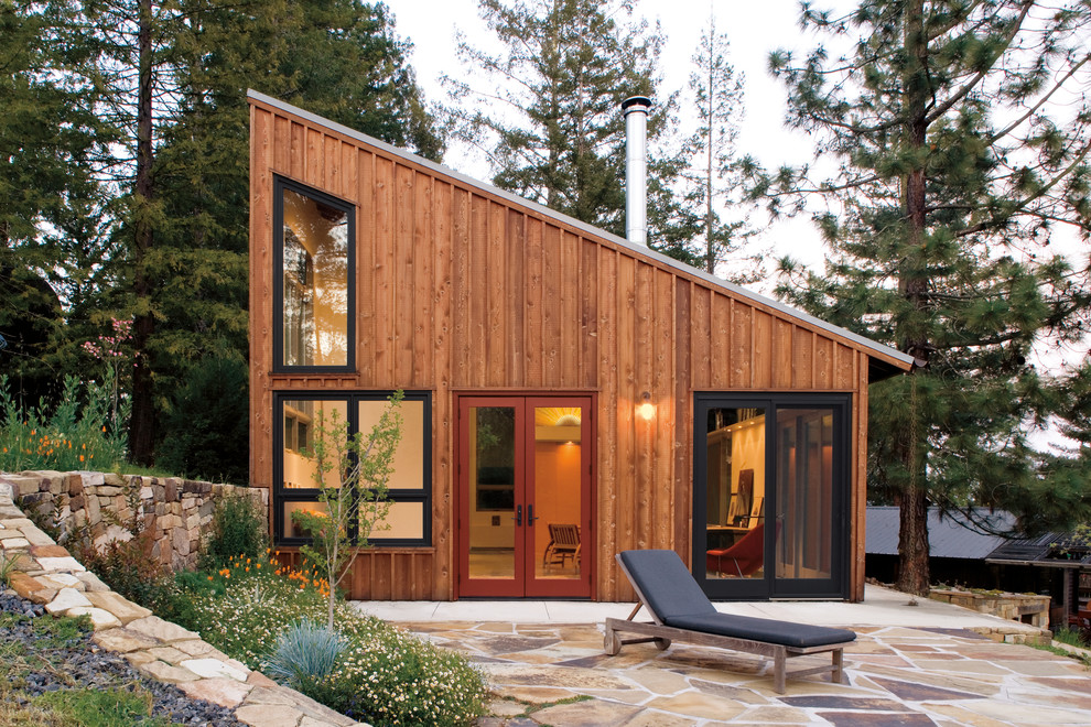 Cette image montre une façade de maison chalet en bois de plain-pied avec un toit en appentis.