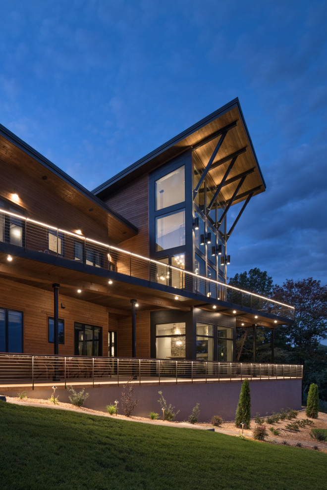 Idée de décoration pour une grande façade de maison marron design en bois à deux étages et plus avec un toit papillon, un toit en métal et un toit marron.