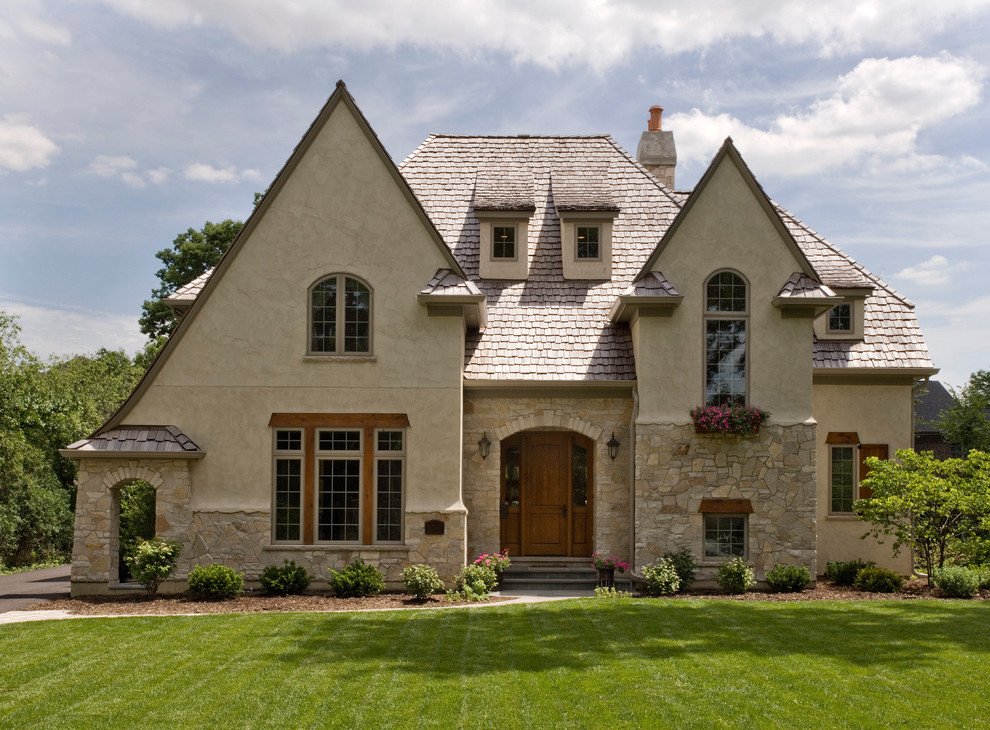 На фото: большой, двухэтажный, бежевый дом в классическом стиле с облицовкой из цементной штукатурки и двускатной крышей с