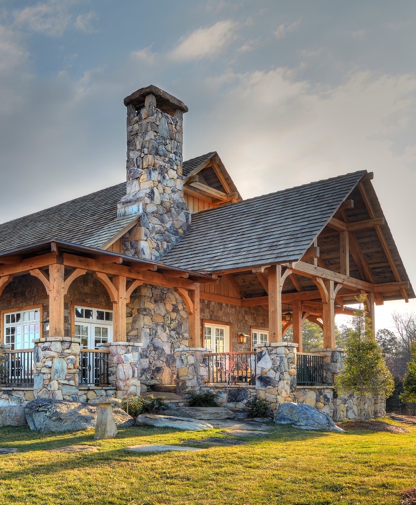 Large mountain style gray two-story stone exterior home photo in Other