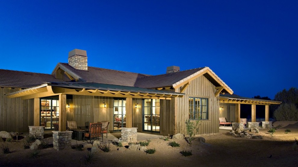 Inspiration for a brown rustic bungalow house exterior in Phoenix with wood cladding.