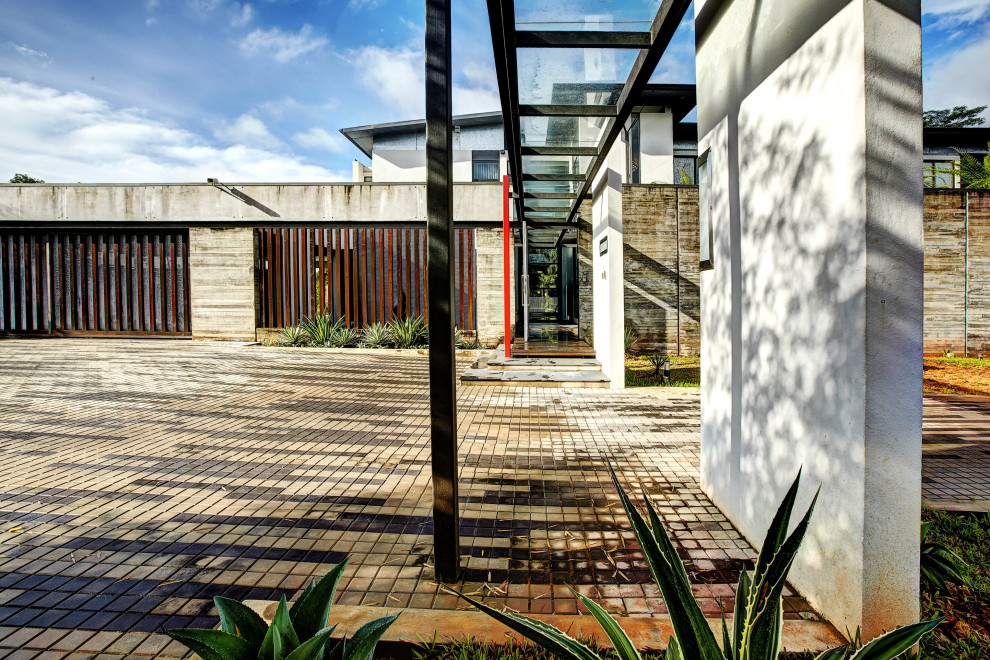 Réalisation d'une grande façade de maison multicolore minimaliste en béton à un étage avec un toit plat et un toit en métal.