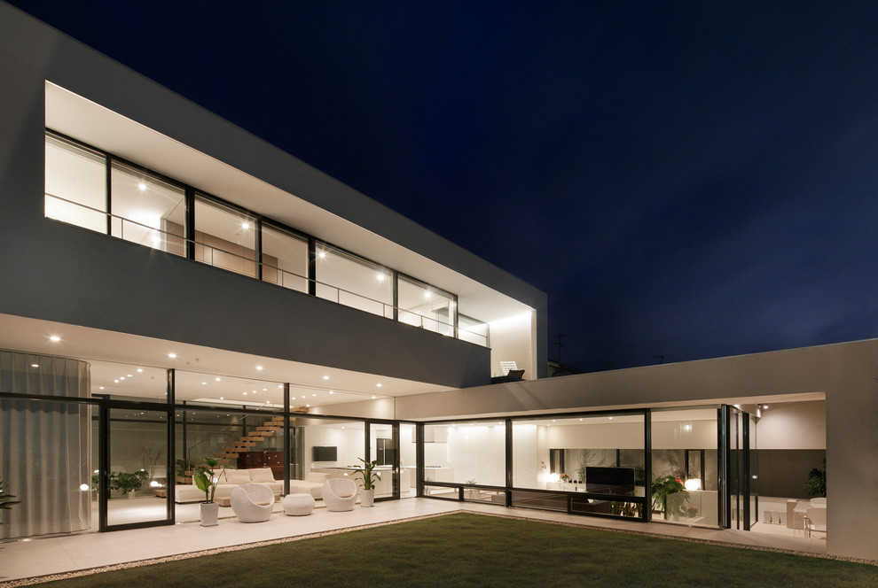 Diseño de fachada blanca moderna de dos plantas con revestimiento de vidrio y tejado plano