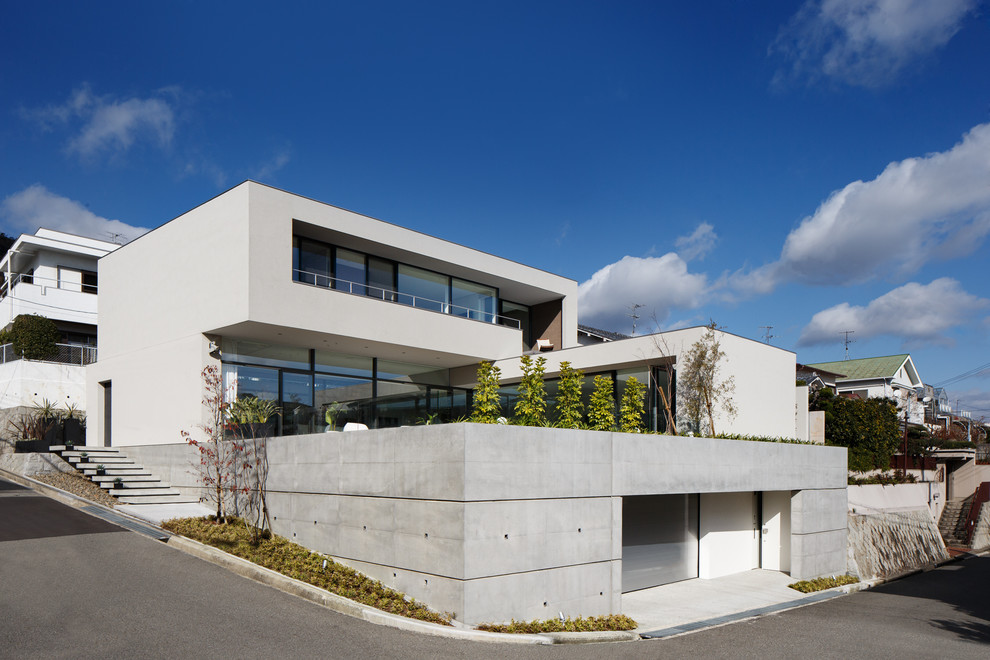 Esempio della facciata di una casa bianca moderna a tre piani con tetto piano e rivestimento in cemento