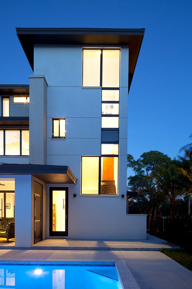 This is an example of a large and beige modern render house exterior in Tampa with three floors and a flat roof.
