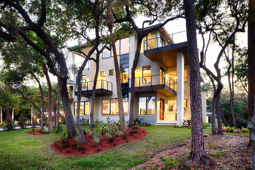 Inspiration for a large and beige modern render house exterior in Tampa with three floors and a flat roof.