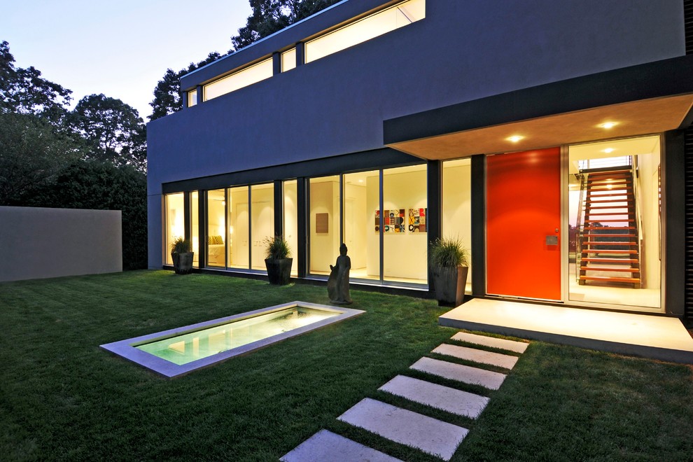 Cette photo montre une grande façade de maison grise moderne en stuc à un étage avec un toit plat.