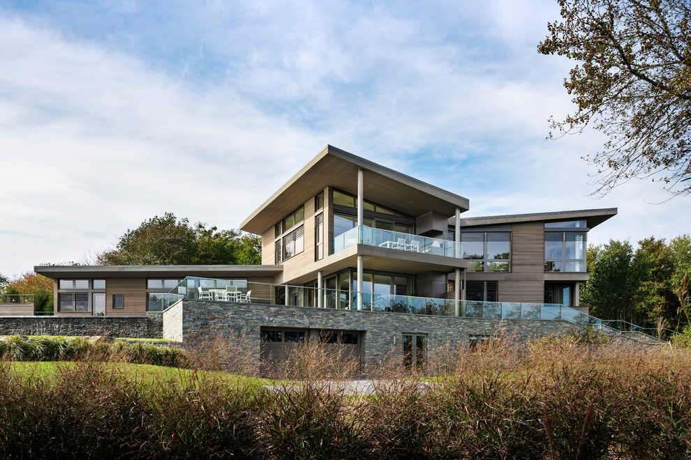 Aménagement d'une grande façade de maison grise moderne en bois à deux étages et plus avec un toit en appentis.