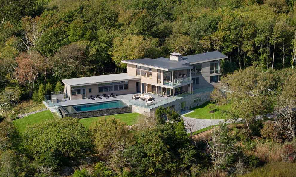 Cette image montre une grande façade de maison grise minimaliste en bois à deux étages et plus avec un toit plat.
