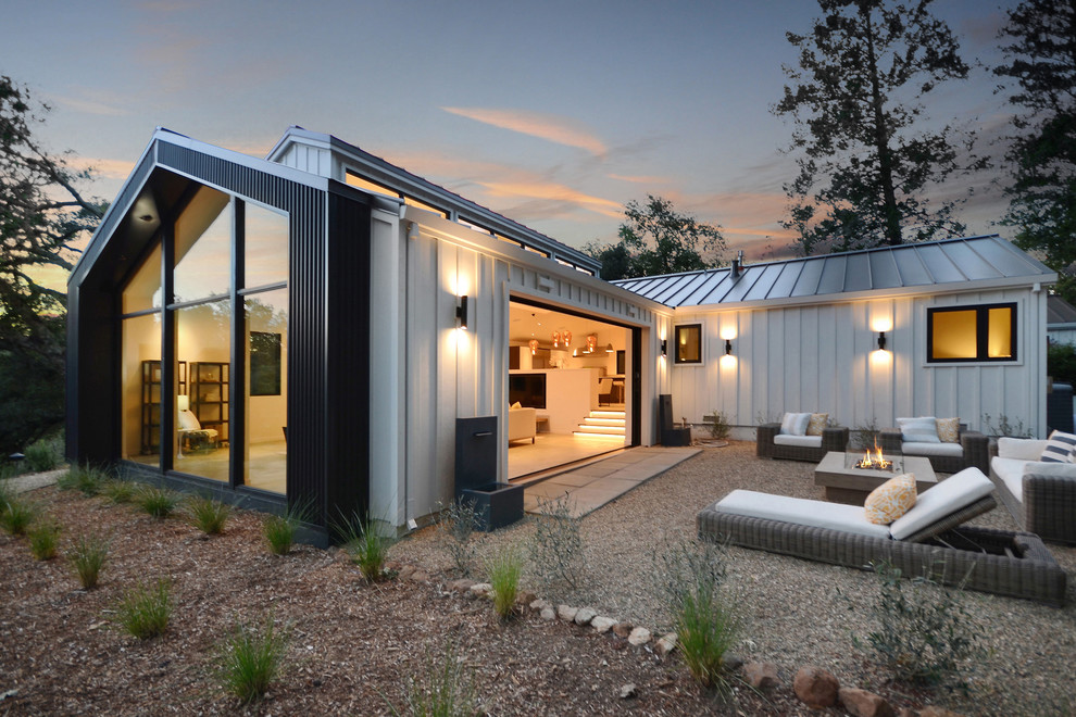 Idee per la villa bianca country a un piano con rivestimento con lastre in cemento, tetto a capanna e copertura in metallo o lamiera
