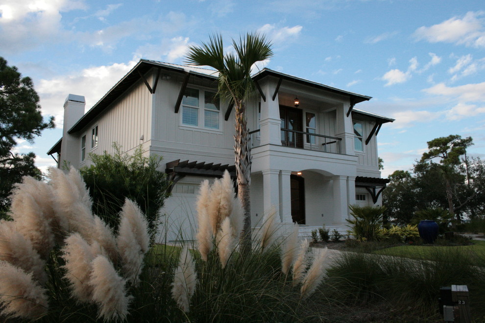 Foto de fachada blanca costera grande de dos plantas con revestimiento de estuco y tejado a dos aguas
